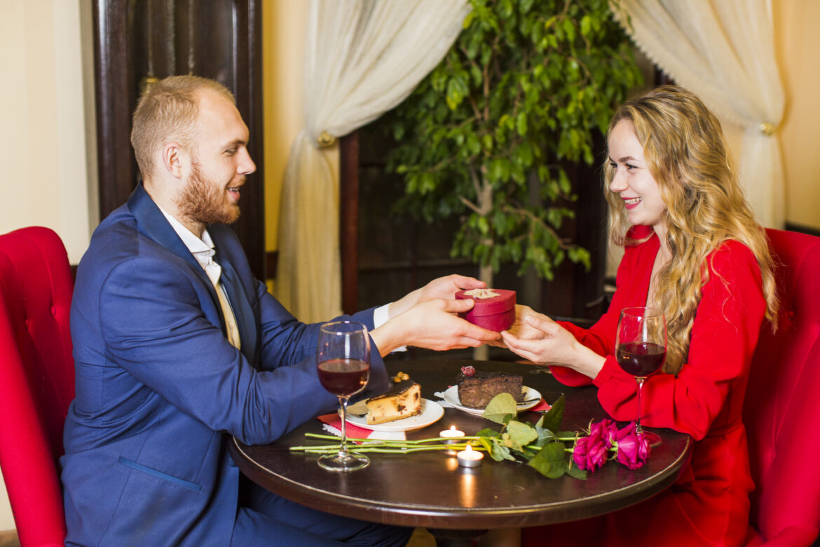 homme-donnant-une-boite-cadeau-en-forme-de-coeur-pour-femme-a-la-table
